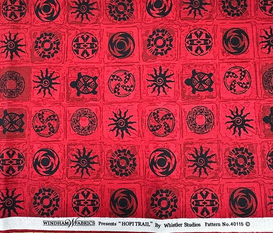 Red fabric with black geometric patterns in a grid layout.