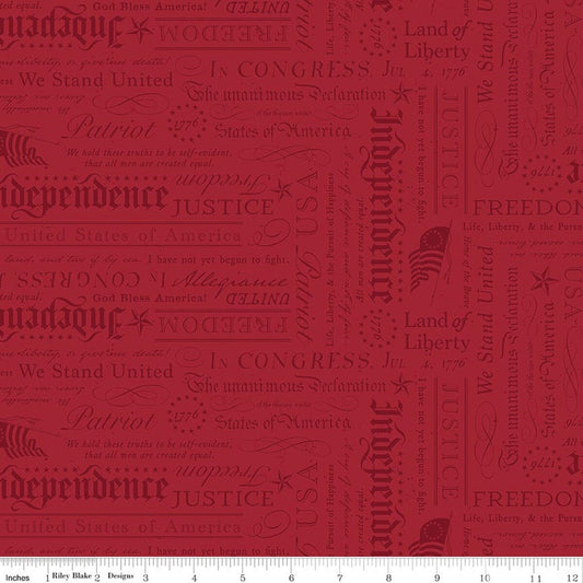 A close-up of a repeating fabric pattern featuring vintage American-themed typography with words like 'Independence,' 'Liberty,' 'Justice,' 'Patriot,' and 'We Stand United' in muted red tones on a warm red background.