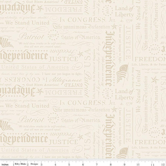 A close-up of a repeating fabric pattern featuring vintage American-themed typography with words like 'Independence,' 'Liberty,' 'Justice,' 'Patriot,' and 'We Stand United' in muted beige and taupe tones on a warm off-white background.