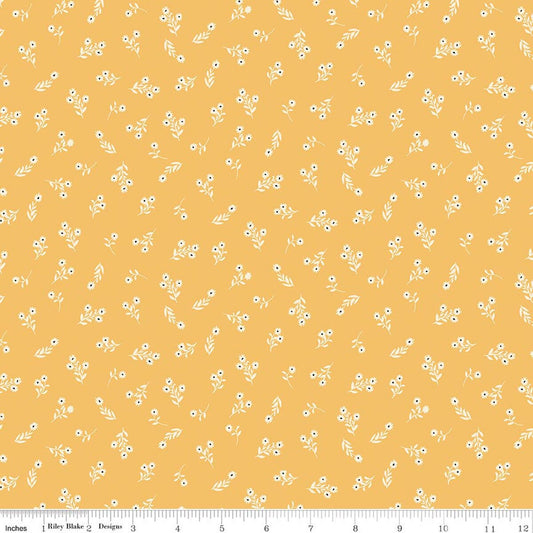 A repeating fabric pattern of small white flowers and leaves on a warm mustard-yellow background