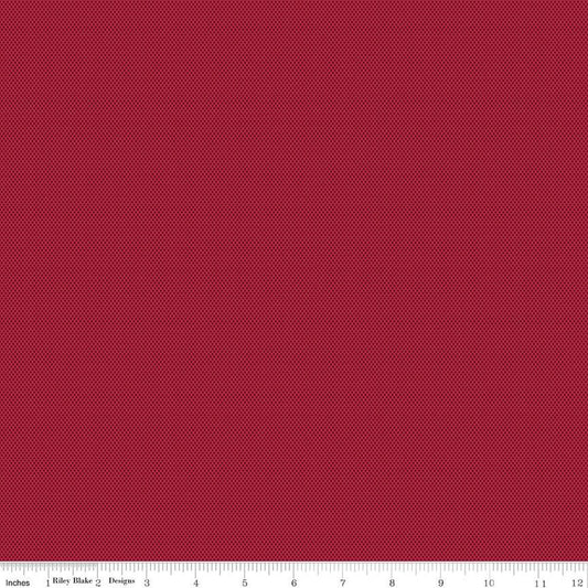 A close-up of a red fabric texture with a pattern of tiny dark red dots